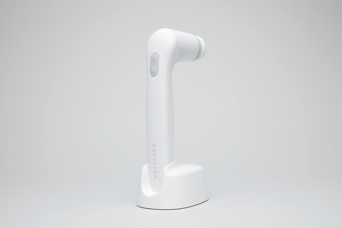White DAS NOVAFON sound wave device with disk attachment, upright in its charging stand