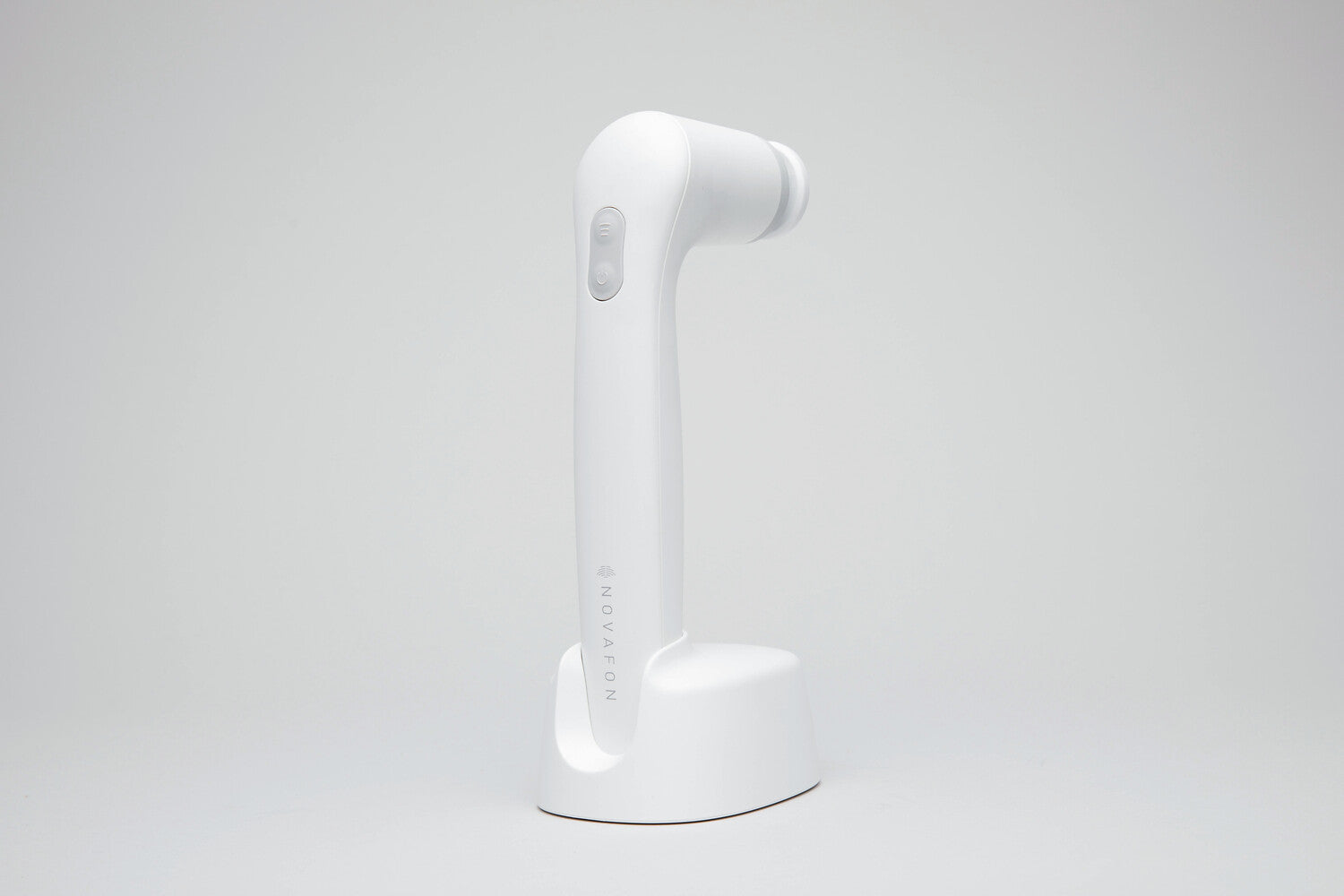 White DAS NOVAFON sound wave device with disk attachment, upright in its charging stand