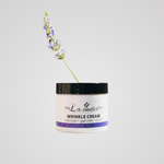 The Lavender Farm wrinkle cream in a white jar with shea butter, goat's milk and vitamin E, with a lavender sprig